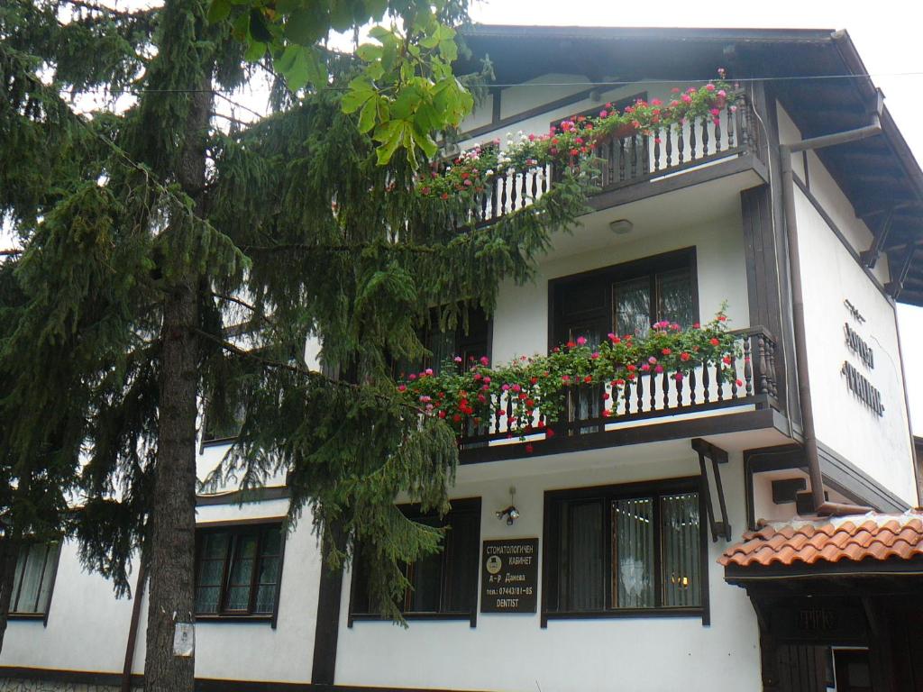 a white building with flowers on the balconies at Къща за гости Типик in Bansko