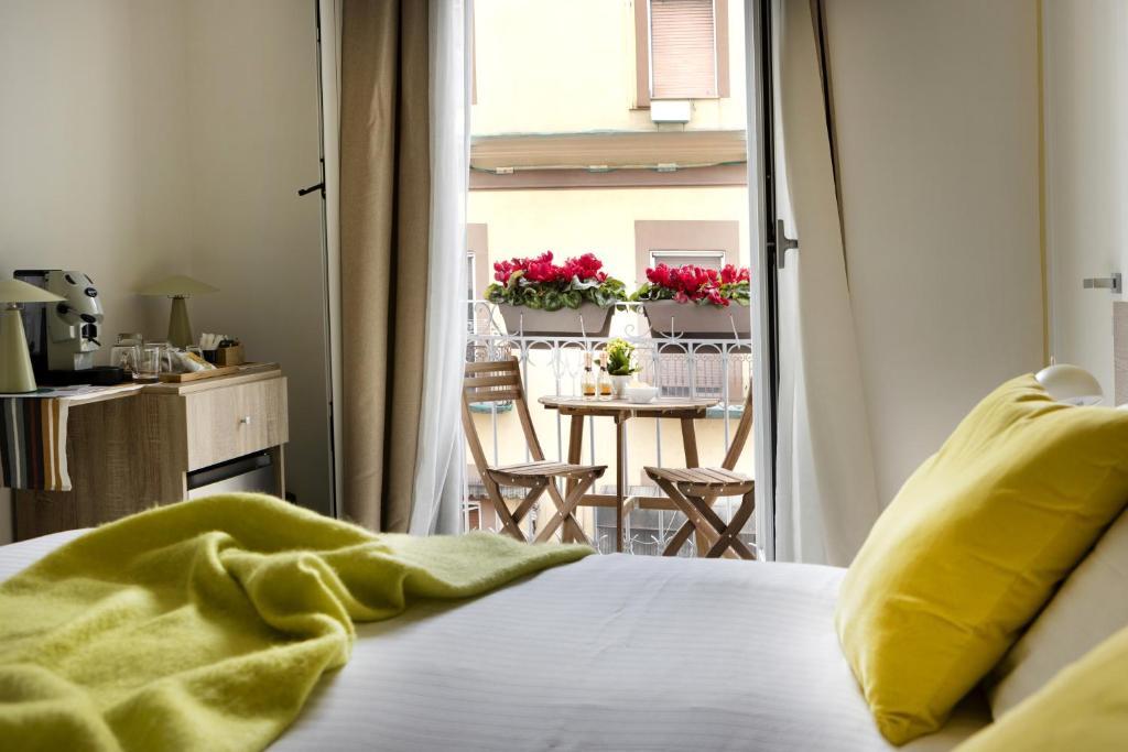 bedroom with yellow pillows and blanket, small wooden table and chairs on balcony with red flowers