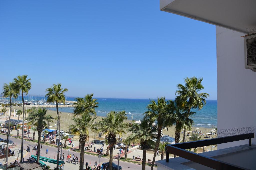 Blick auf einen Strand mit Palmen und das Meer in der Unterkunft Sunorama Beach Garden 302 in Larnaka