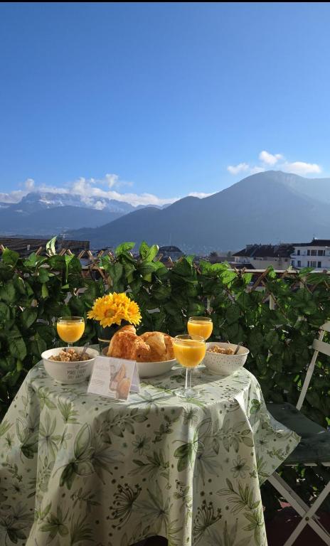 une table avec une assiette de nourriture et deux verres de jus d'orange dans l'établissement Martine a Annecy parking vue magnifique, à Annecy
