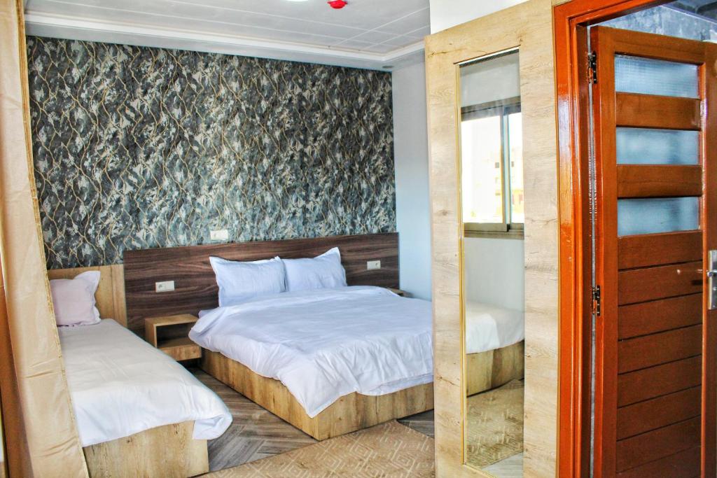een slaapkamer met 2 bedden en een glazen schuifdeur bij Palmiers Hôtel Club in Er Rachidia