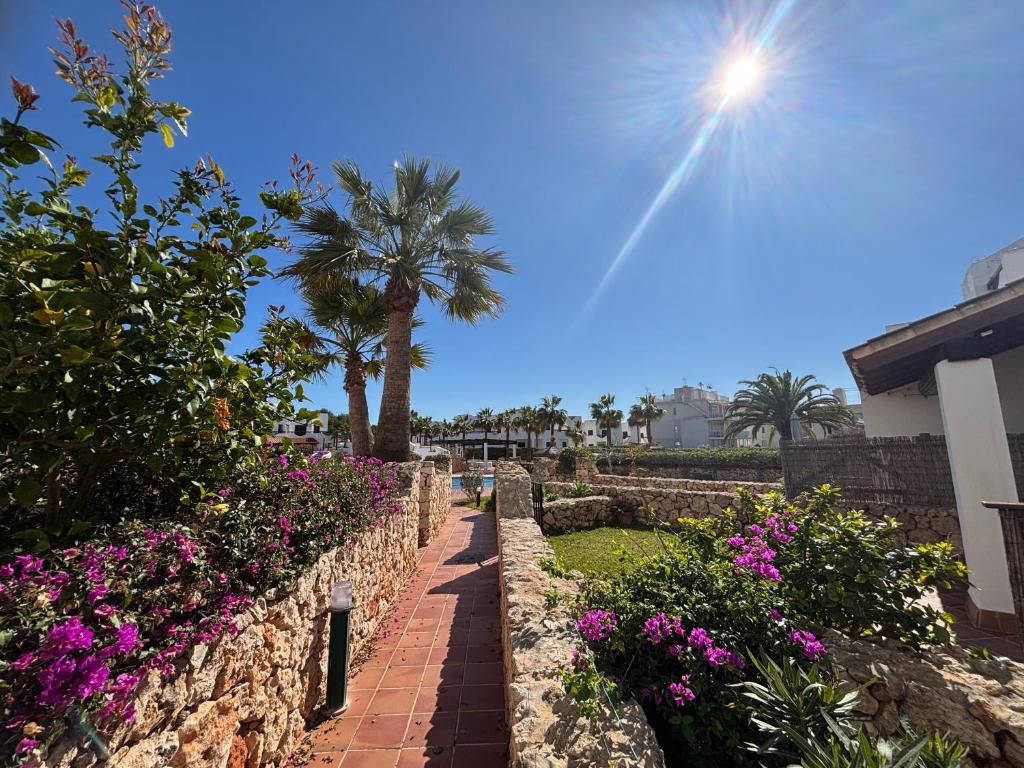 een stenen muur met bloemen en een palmboom bij Hippie und Famila Paraiso in Cala d´Or