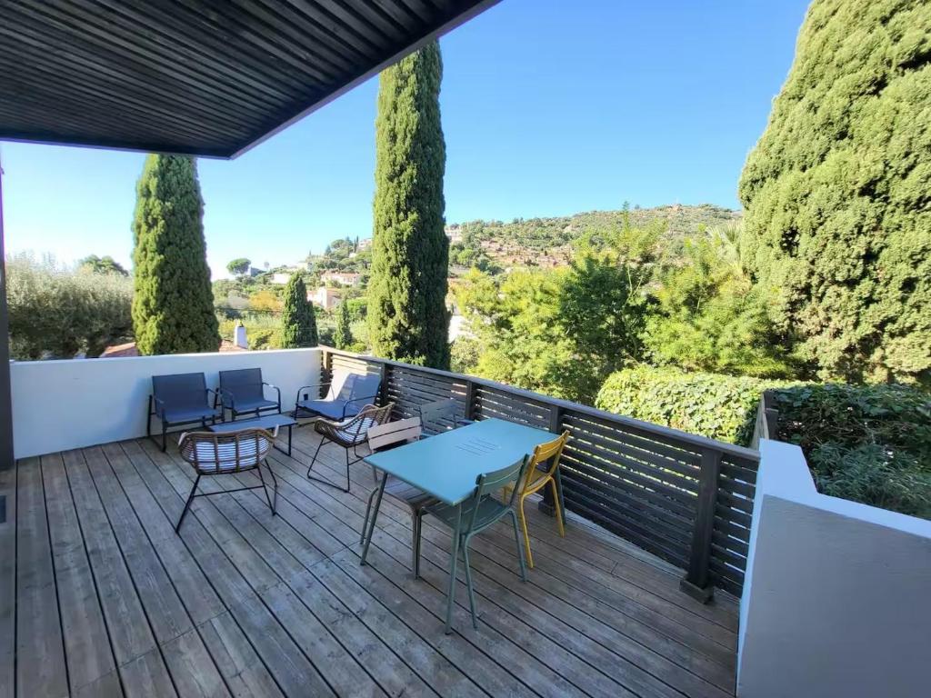 una terrazza con tavoli, sedie e alberi di La Fossette - T2 avec terrasse, parking et wifi a Le Lavandou