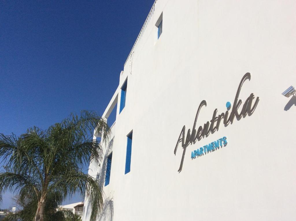 um sinal na lateral de um edifício com uma palmeira em Aphentrika Apartments em Protaras