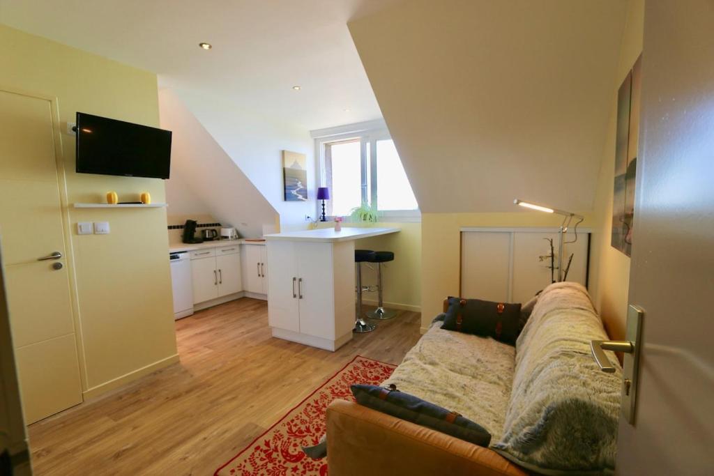 un salon avec un canapé et une cuisine dans l'établissement Cozy apartment with exceptional sea view - CANCALE, à Cancale