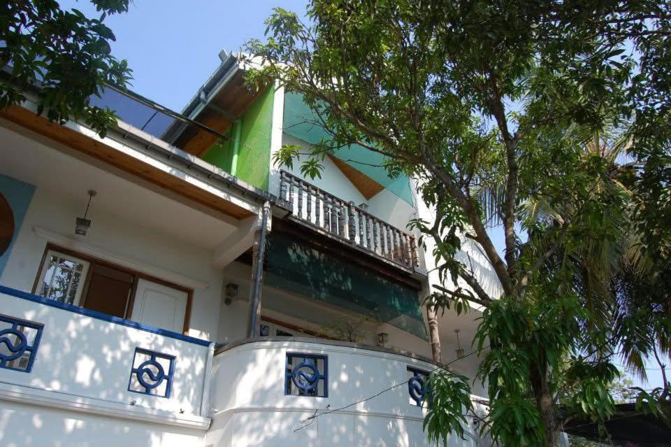 een wit huis met een boom ervoor bij Orchid Villa in Negombo