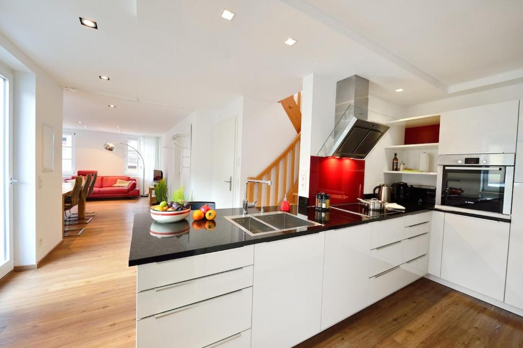 Una cocina con gabinetes blancos y una encimera negra. en Altstadtapartment Himmelreich, en Heidelberg