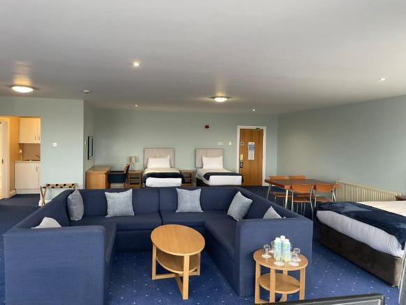 a living room with a blue couch and two beds at Inn On The Coast in Portrush