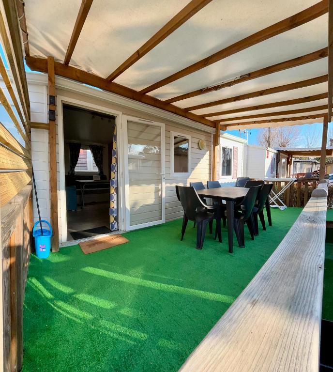 - une terrasse avec une table et des chaises sur un sol verdoyant dans l'établissement Vias Mobil home 6-8 pers tout confort climatisé, à Vias