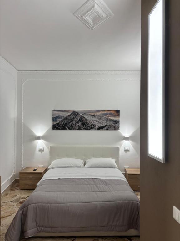 a white bedroom with a large bed and two night stands at Appartamento San Vito in Piana degli Albanesi