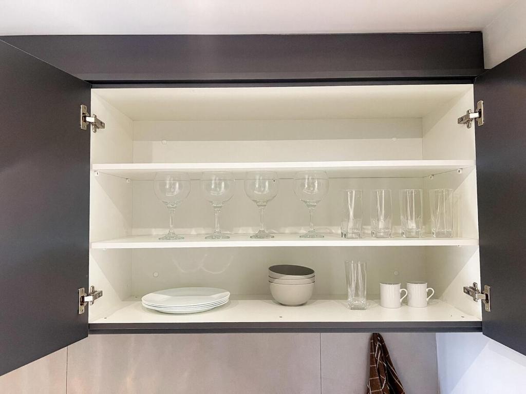 a cupboard filled with lots of glasses and dishes at Modern Studio Brooklin 230 meters from the subway in Sao Paulo