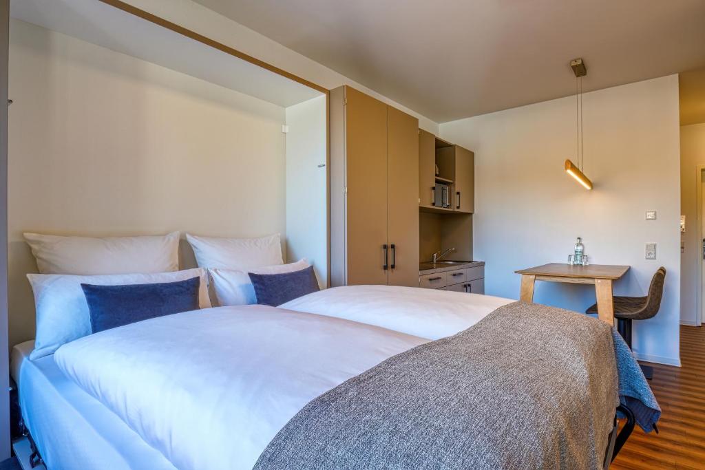 Un dormitorio con una gran cama blanca y una mesa. en Nicetostay Aparthotel, en Bremen