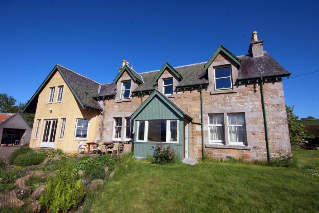 una gran casa de piedra en un campo de hierba en Netherton Farm B&B, en Culbokie