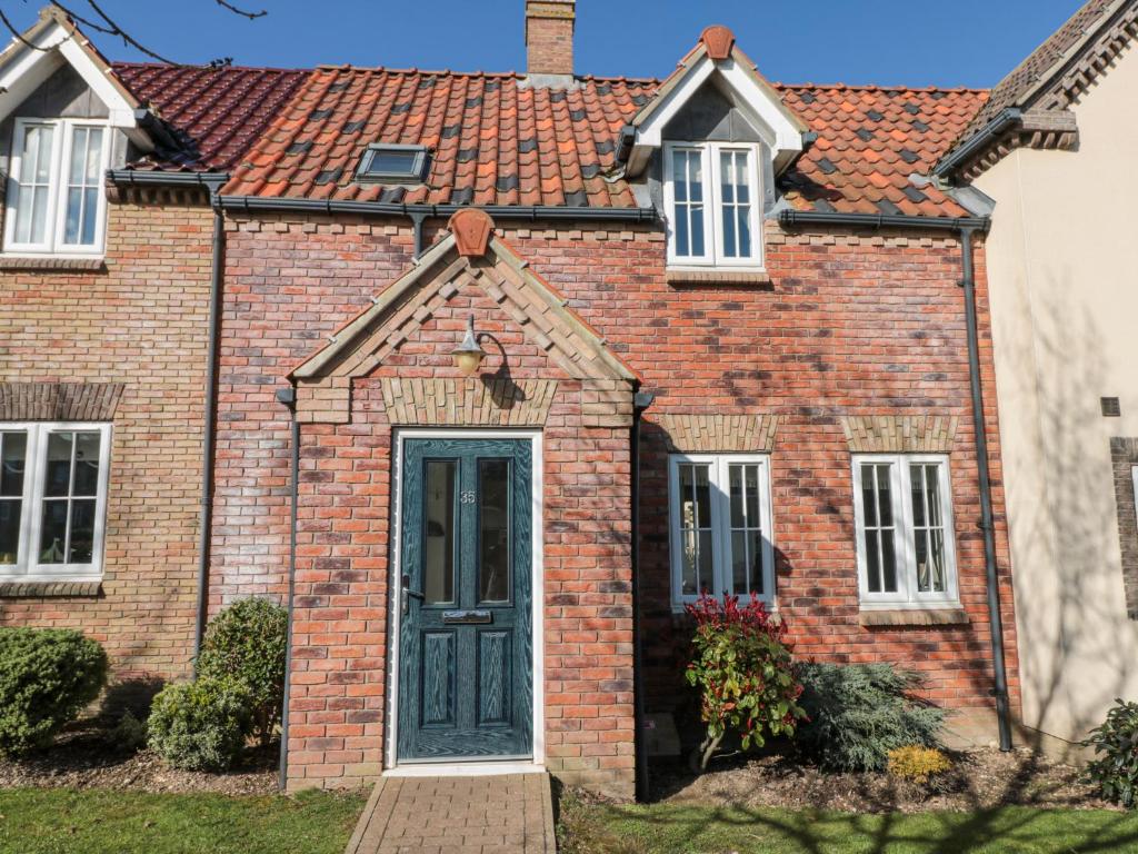 a brick house with a green door at Dotty's Sunshine Cottage in Reighton
