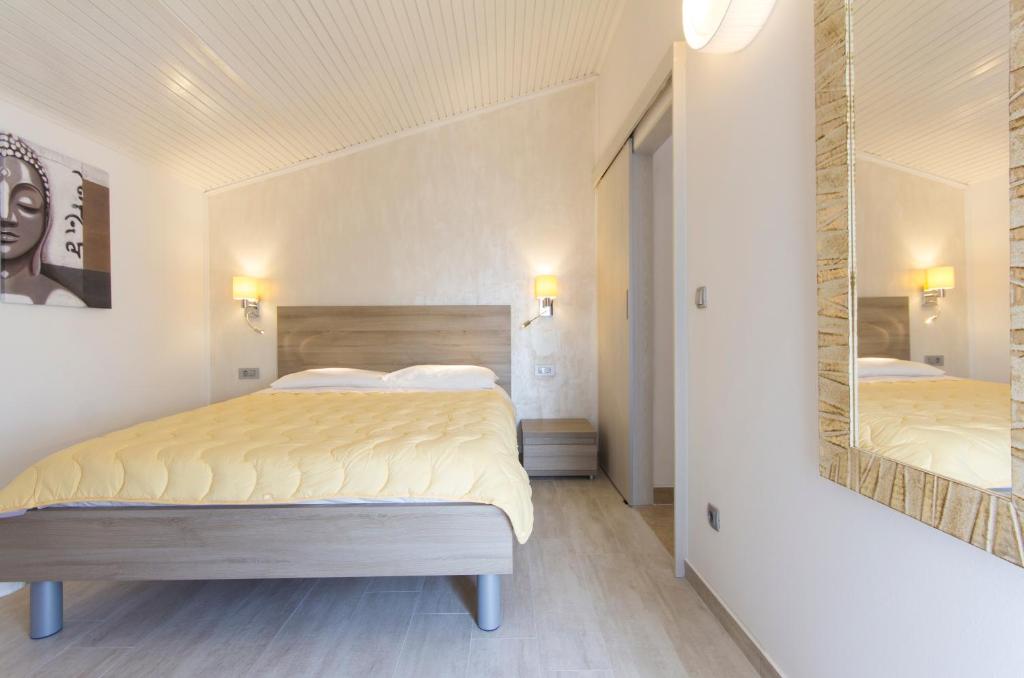a bedroom with a large bed and a mirror at Alison Apartments in Premantura