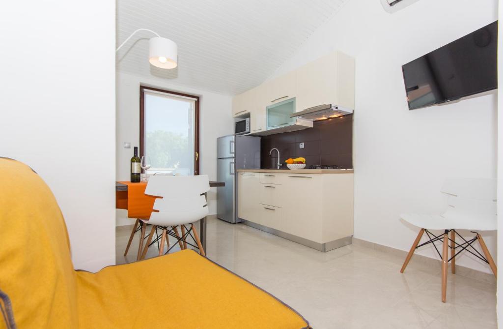 a kitchen with a table and chairs in a room at Alison Apartments in Premantura