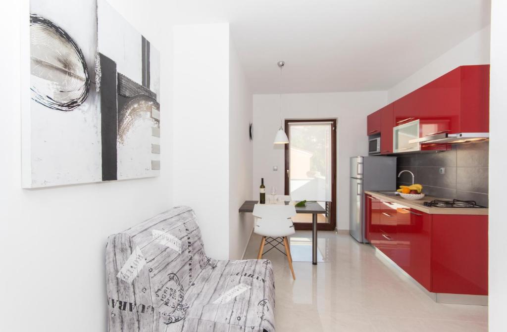 a kitchen with red cabinets and a chair in a room at Alison Apartments in Premantura