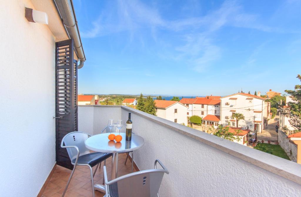 a balcony with a table and chairs and a bottle of wine at Alison Apartments in Premantura