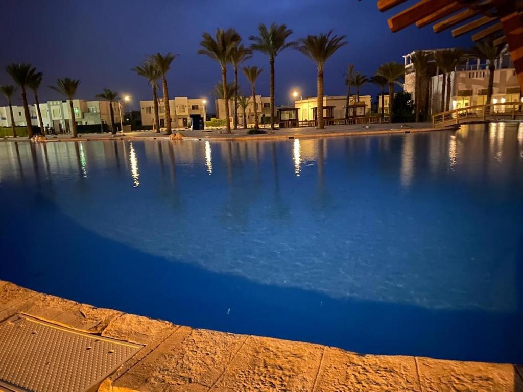a large swimming pool at night with palm trees at Luxurious 3BR Chalet Aqua Park View Amwaj in El Alamein