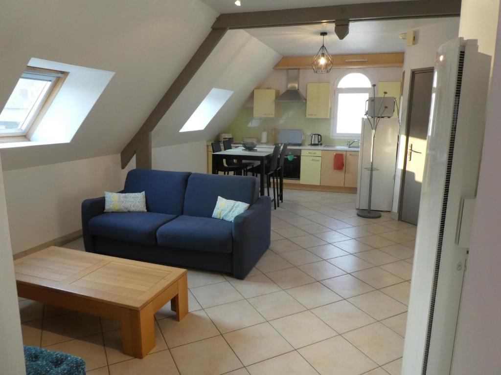 un salon avec un canapé bleu et une table dans l'établissement LE BRIDGE, à Bénouville