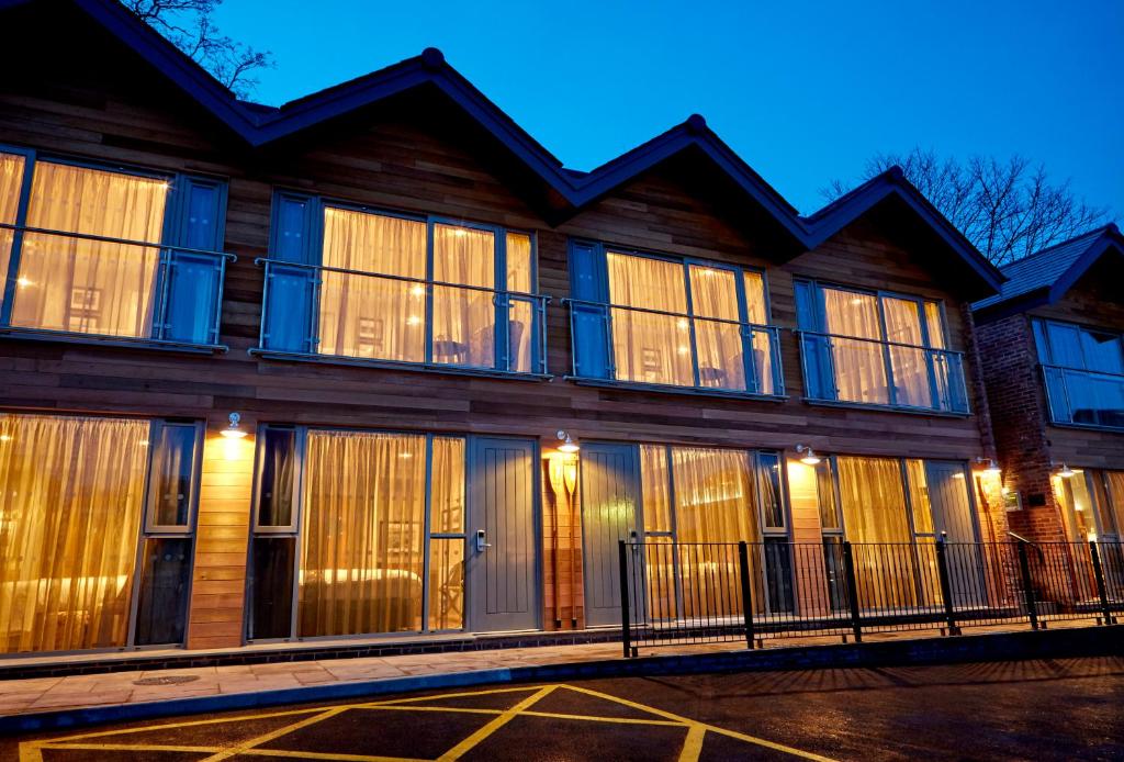 een groot houten gebouw met grote ramen in de nacht bij The Boathouse Inn & Riverside Rooms in Chester