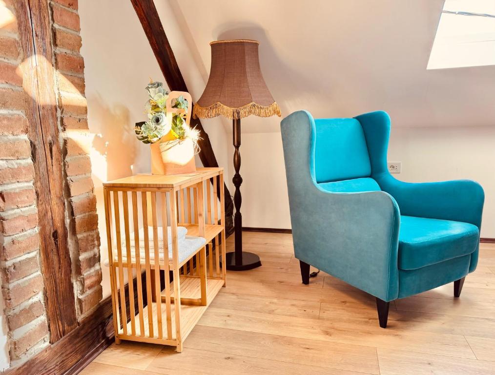 a living room with a blue chair and a lamp at Apartment By the River in Niš