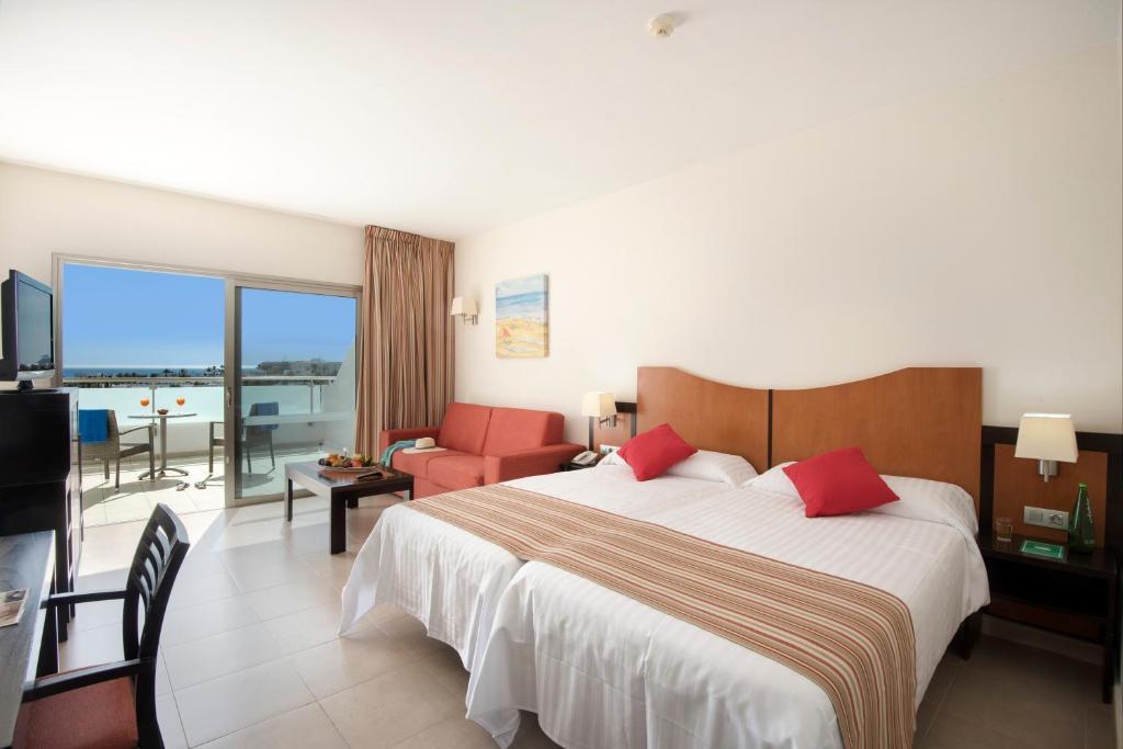 a hotel room with a large bed and a balcony at Hotel Lanzarote Village in Puerto del Carmen