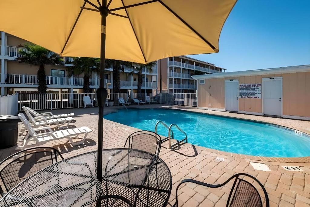 a pool with chairs and an umbrella in front of a building at Across the Street from beach with 2 pools in Panama City Beach