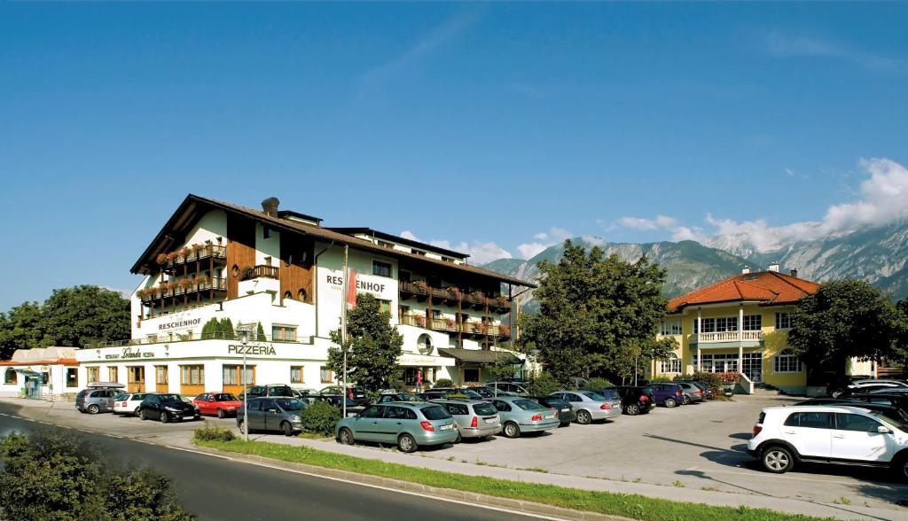 un estacionamiento con autos estacionados frente a un edificio en Der Reschenhof, en Mils bei Hall