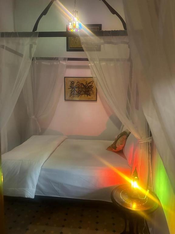 Dormitorio pequeño con cama con luz de arco iris en Room 3 Riad Khadija With Breakfast, en Rabat