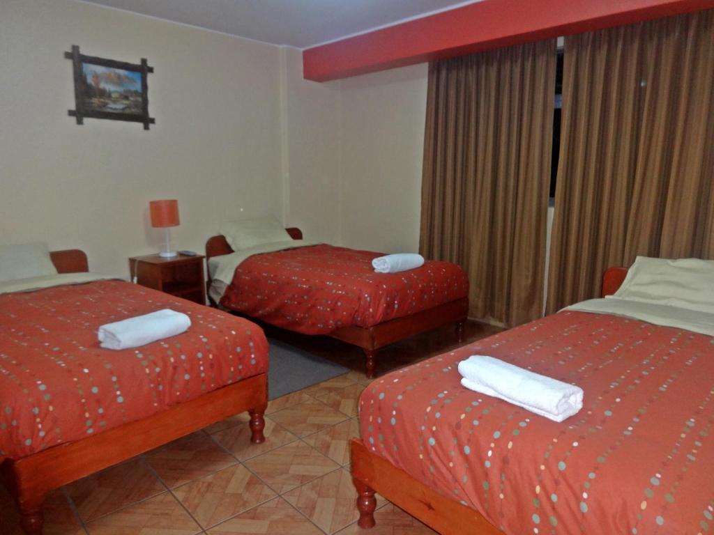 una camera d'albergo con due letti con lenzuola rosse di Hatun Wasi Huaraz a Huaraz