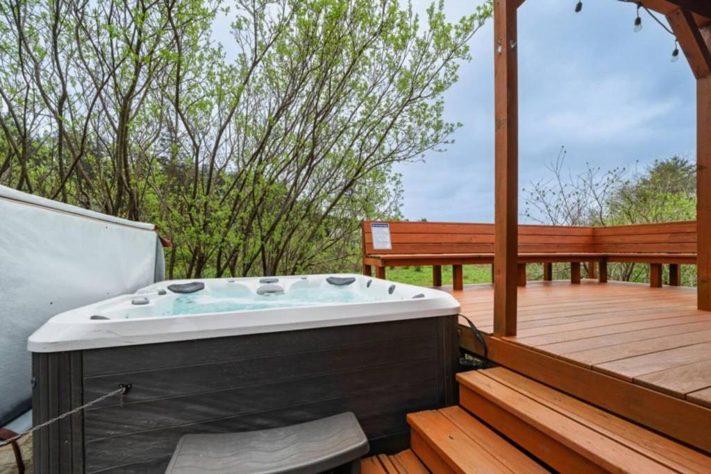 een hot tub op een houten terras met een bank bij 3BR Hot Tub Ocean Views & King Beds Near Beach in Nehalem