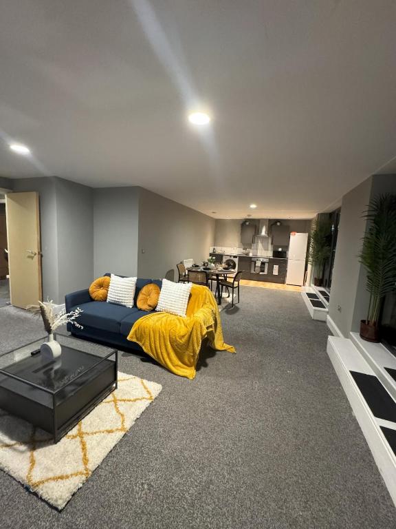 a living room with a blue couch with a yellow blanket at Ancoats 2BR with Private terrace in Manchester