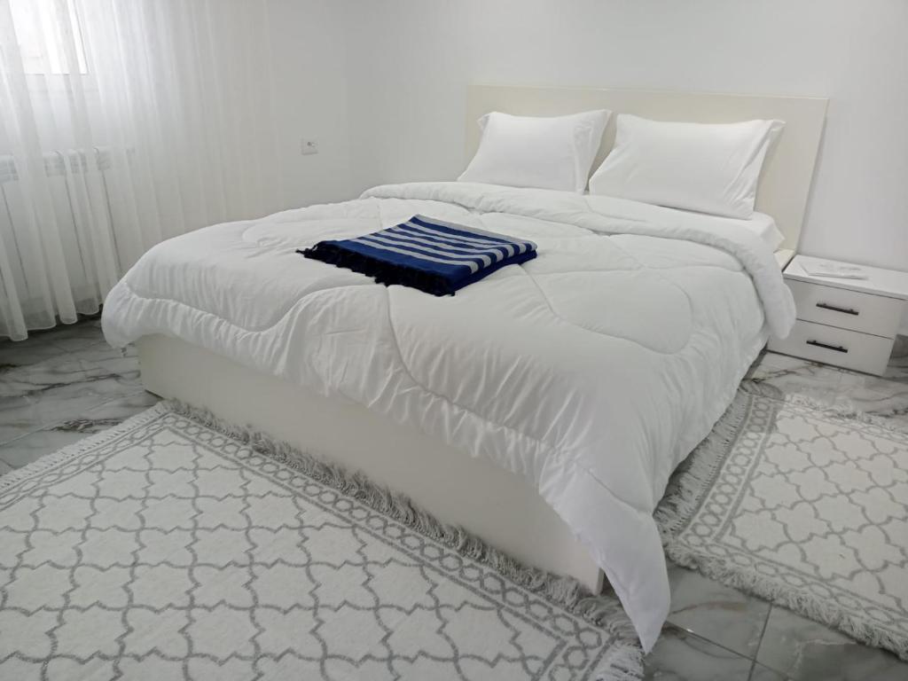 a white bed with white sheets and a blue blanket at Olivia in La Marsa