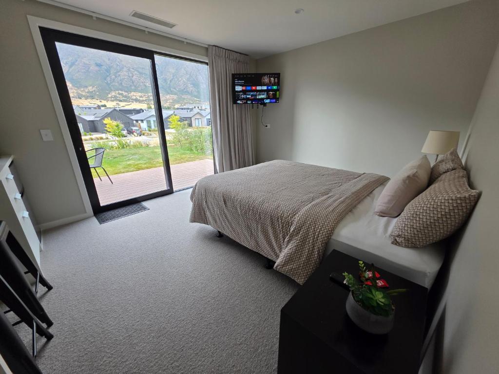 een slaapkamer met een bed en een glazen schuifdeur bij Loop the Loop in Queenstown