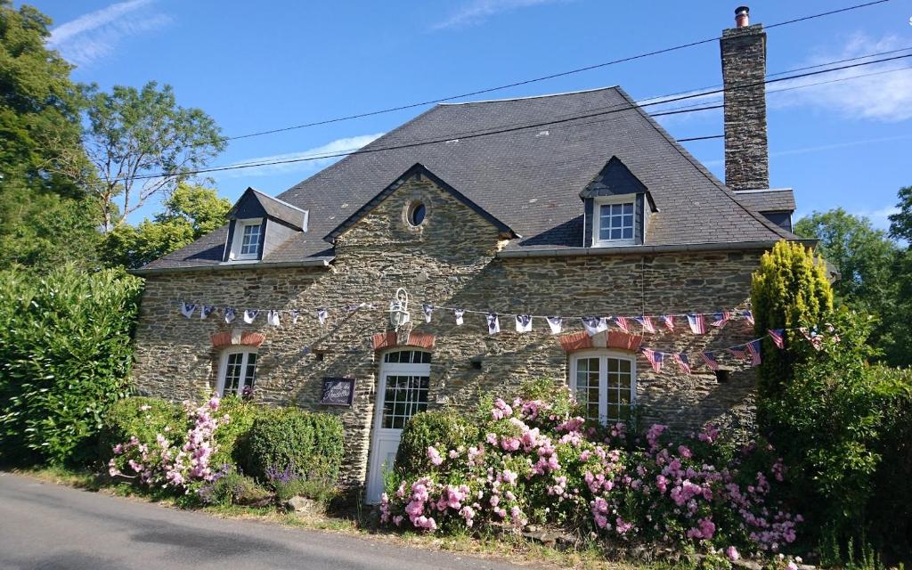 a stone house with flowers in front of it at Moulin des Rondelles in Cerisy-la-Forêt