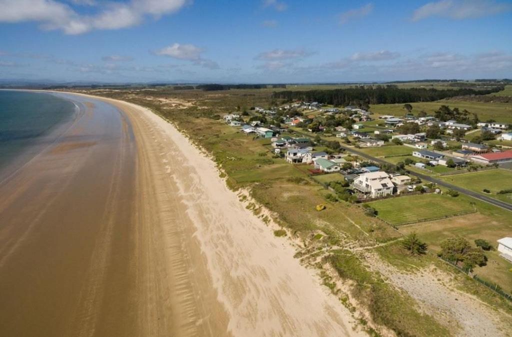 an aerial view of a beach with houses and the ocean at Pyramid beach house in Karikari Peninsula