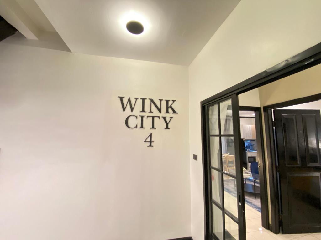 un mur blanc avec un panneau indiquant la ville à treillis dans l'établissement Wink City 4th Patong, à Patong Beach