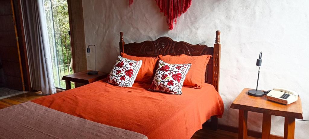 - une chambre avec un lit doté de draps et d'oreillers orange dans l'établissement Villa do Sol, à Conceição da Ibitipoca