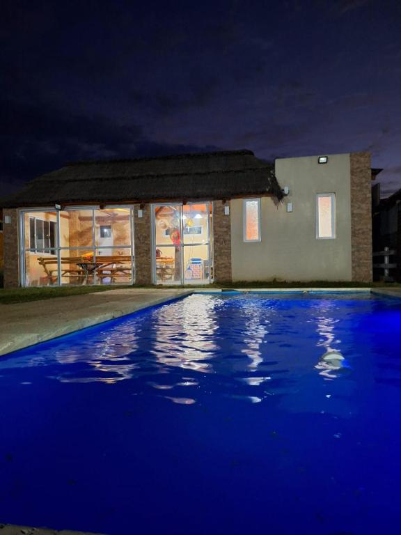 a swimming pool at night with a house at Casa 3 dormitorios en Barrio Privado con vigilancia en Haras el Terraplen, General Rodriguez, con Pileta, quincho, parrilla in General Rodríguez