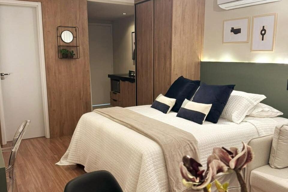 a bedroom with a large bed with blue and white pillows at Charmoso, moderno e central! 11 in Poços de Caldas
