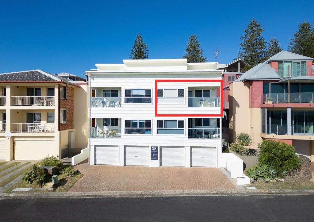 a white house with a red stripe on it at Avalon 3 in Yamba