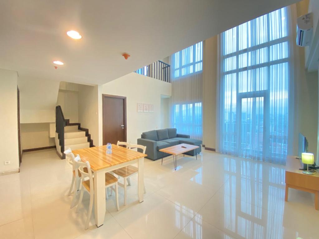 a living room with a table and a couch at Fabulous 2BR Loft Apartment with Private Bathub at El Royale By Travelio in Bandung