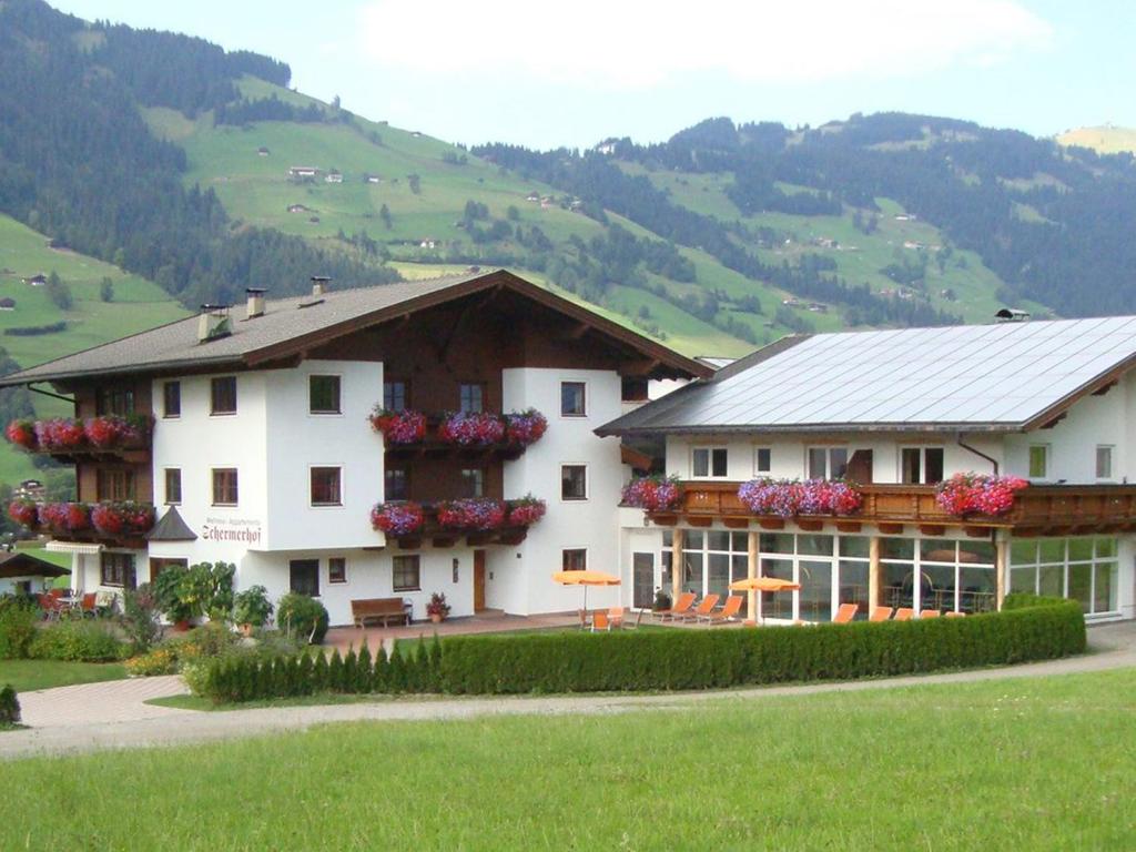 ein großes weißes Gebäude mit Blumen an den Fenstern in der Unterkunft Activ Wellness - Appartement Schermerhof in Westendorf