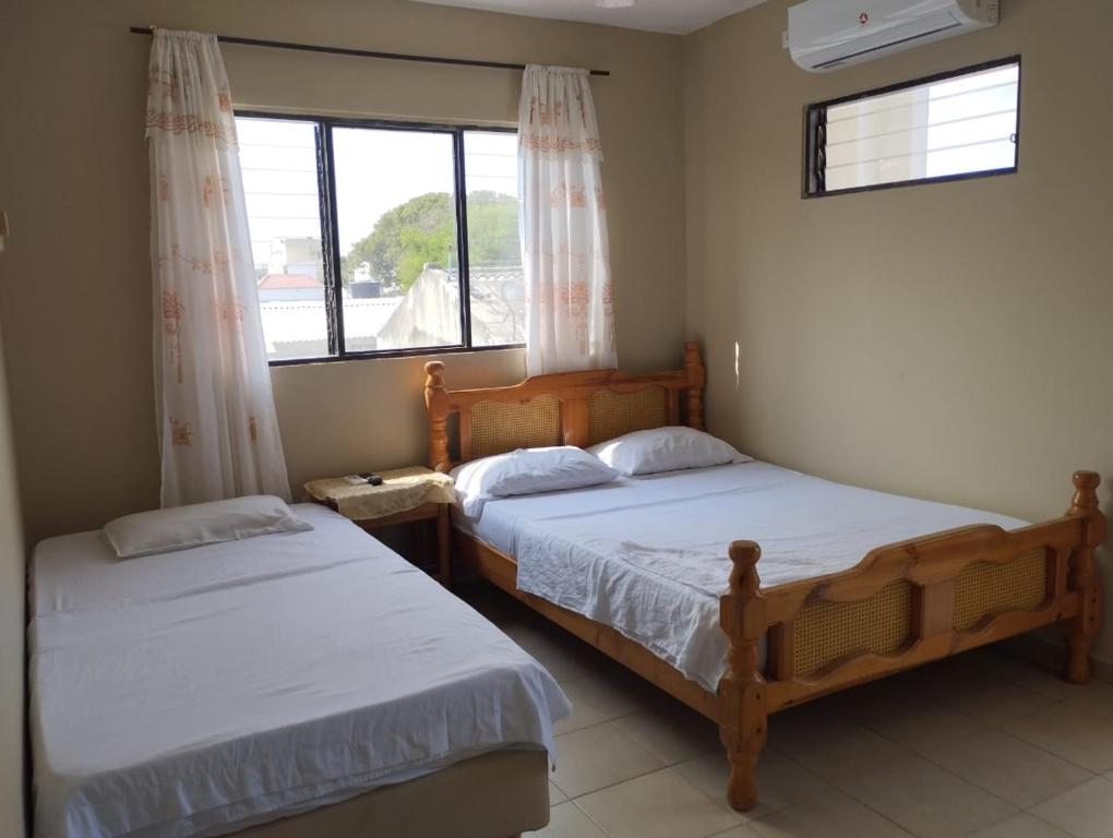 two beds in a bedroom with a window at Hotel Almirante Padilla in Ríohacha