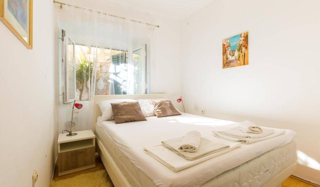 1 dormitorio con 1 cama blanca grande y ventana en Dubrovnik center apartment, en Dubrovnik