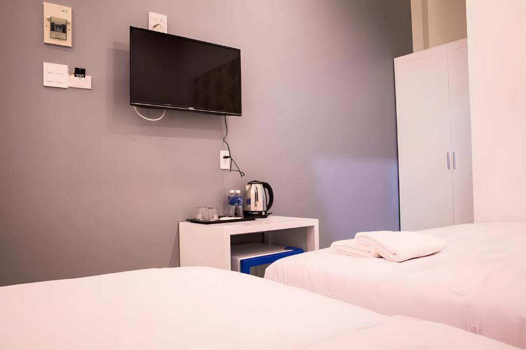 a room with two beds and a tv on the wall at 1991 Hotel in Phan Thiet