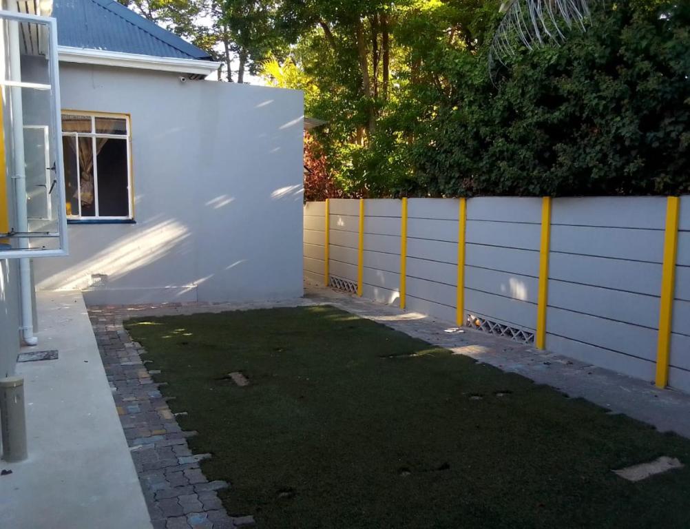 un patio trasero con una valla blanca y un poco de hierba en Neo & Ruks Guest House Boston Belleville 7, en Bellville