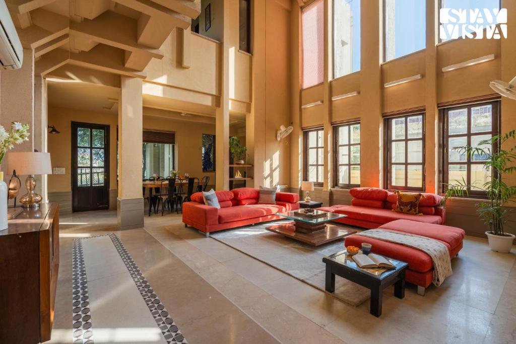 a large living room with red couches and a table at StayVista at Albatross Haven with BBQ & Bonfire in Noida