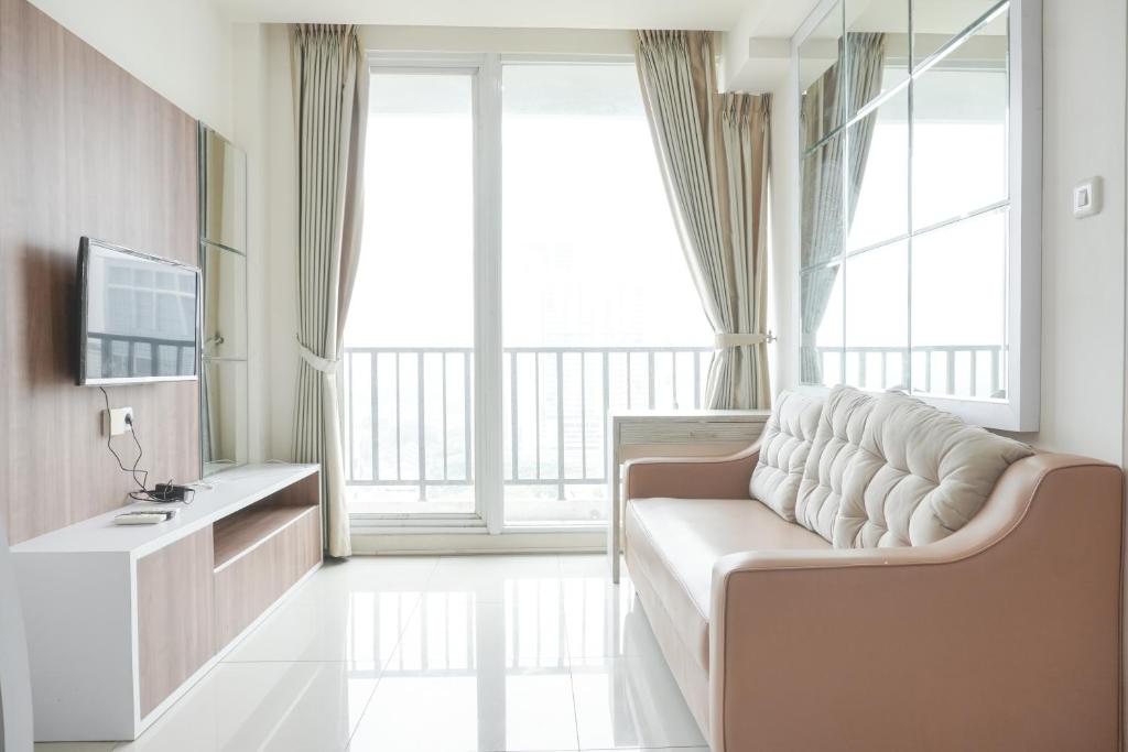 a living room with a couch and a television at Comfort 2BR at Tree Park City BSD Apartment By Travelio in Tangerang